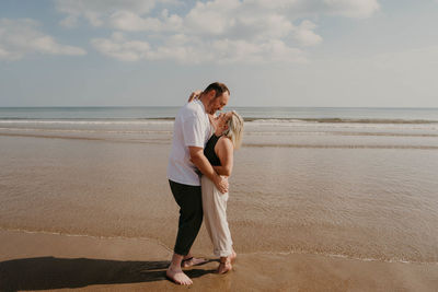 Rear view of woman standing at beach against sky