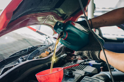 Midsection of man pouring in car