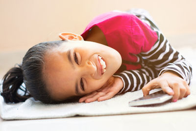 Portrait of smiling girl lying on sofa at home