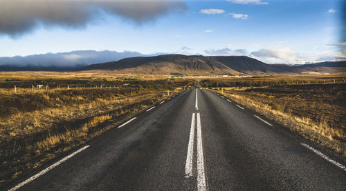 Empty road along landscape and mountains against sky