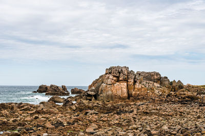 Rock formation on beach against sky