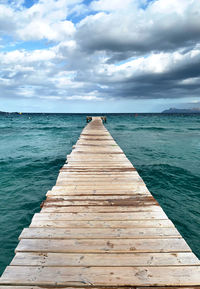 Wooden pier over sea against sky