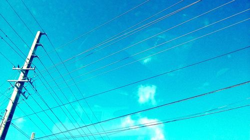 Low angle view of electricity pylon against blue sky