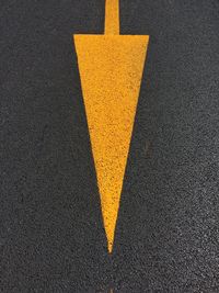 Close-up of yellow arrow symbol on road