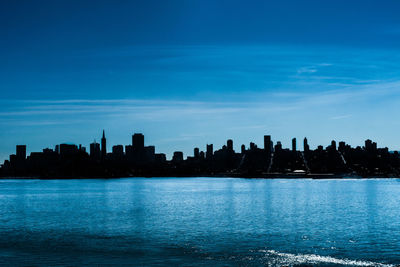 City at waterfront against blue sky