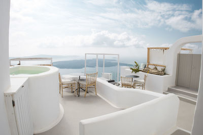 Chairs and table by sea against sky