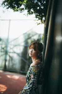 Portrait of woman standing against fence