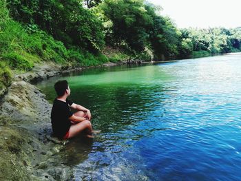Side view of shirtless man relaxing in lake