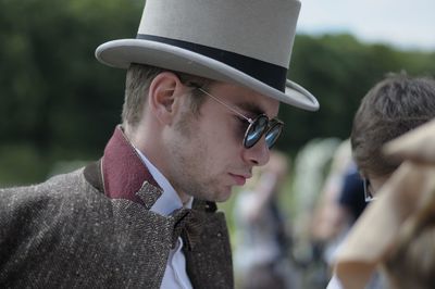 Man wearing hat looking away while standing outdoors