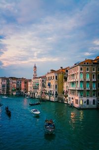 Boats in canal by buildings in city