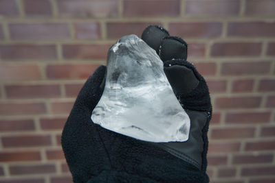 Close-up of person holding ice cream against wall