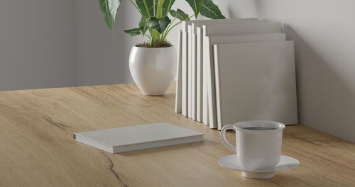 Coffee cup and potted plant on table at home