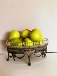 Fruits in basket on table against wall