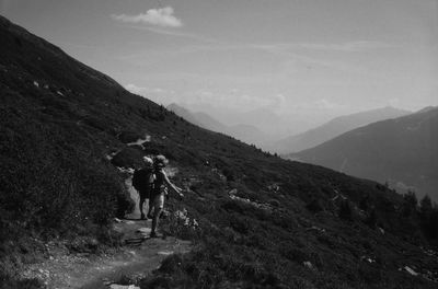 Rear view of man walking on mountain against sky