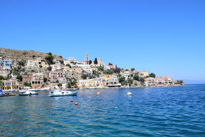 Scenic view of sea by town against clear blue sky