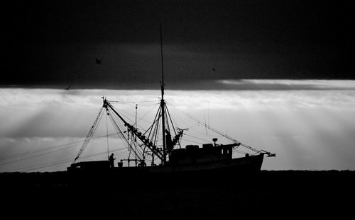 Silhouette sailboat on sea against sky at dusk