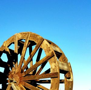 Low angle view of water wheel against clear blue sky on sunny day