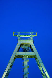 Low angle view of crane against clear blue sky