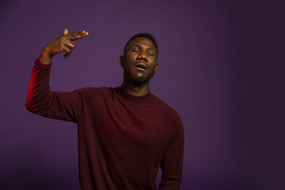 Portrait of young man standing against gray background