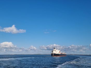 Boat sailing in sea against blue sky