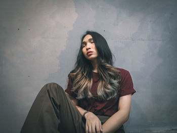 Portrait of beautiful young woman against wall