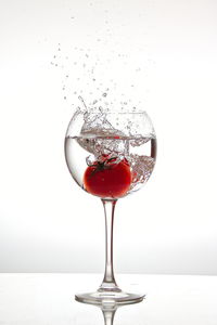 Close-up of wineglass on glass against white background