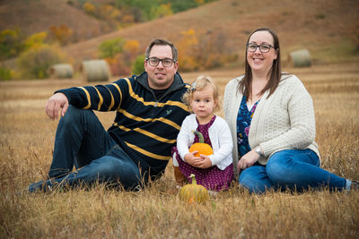 Full length of parents with daughter sitting outdoors