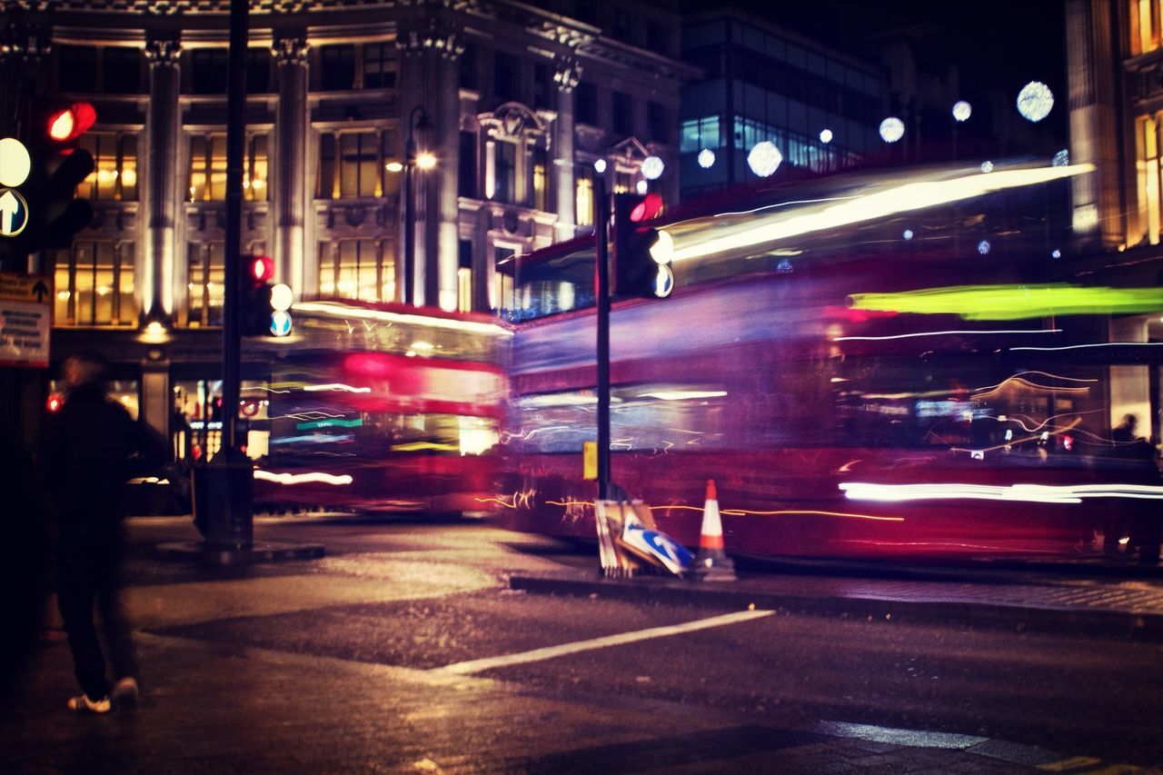 illuminated, night, transportation, street, car, building exterior, land vehicle, city, mode of transport, city street, architecture, city life, built structure, traffic, street light, road, on the move, motion, incidental people, lighting equipment