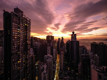 Modern buildings in city against romantic sky at sunset