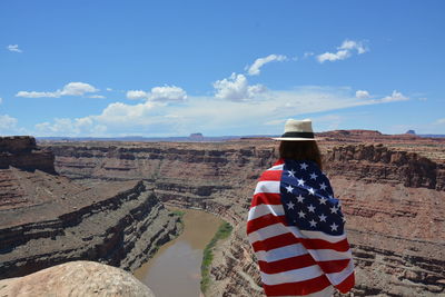 Rear view of woman wrapped in flag standing on mountain