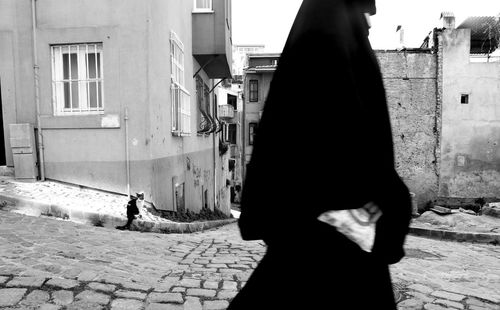 Side view of woman walking on street amidst buildings