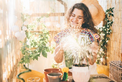 Portrait of smiling young woman with flowers on table at home