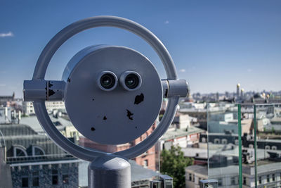 Close-up of coin-operated binoculars against buildings in city