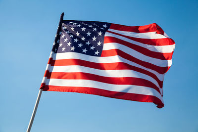 Low angle view of flag against blue sky