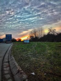 Bare trees in city against sky during sunset