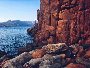 Rock formation by sea against clear sky