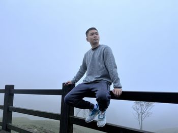 Portrait of young man standing against clear sky