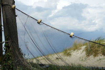 Low angle view of barbed wire fence against sky