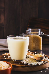 Lactose-free rice milk in a glass and rice cereal on the table vertical view