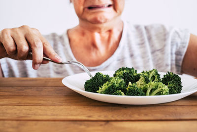 Midsection of woman eating broccoli