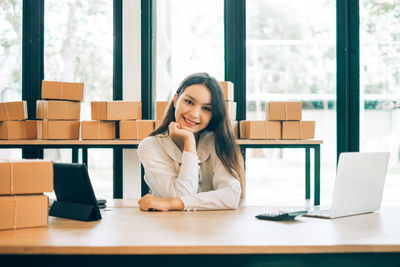 Young woman using mobile phone while sitting on table