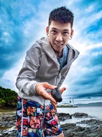 Portrait of man standing at beach against sky