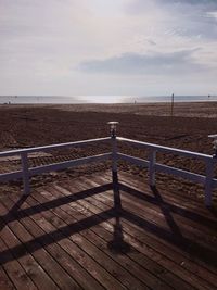 Boardwalk by sea against sky