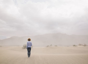 Rear view of woman standing in desert