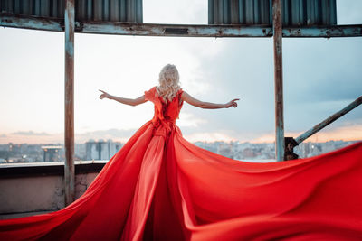 Woman with red umbrella standing against the sky