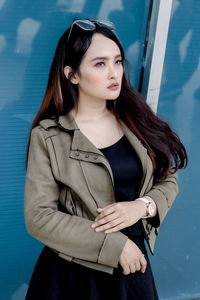 Young woman standing against wall