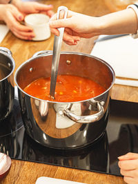 Uncertain woman preparing soup in  kitchen at home. women stirs tomato soup in  saucepan on  stove.