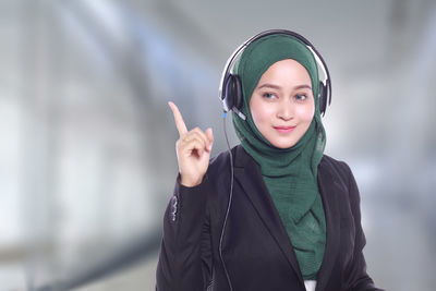 Portrait of confident businesswoman with headphones wearing hijab at call center