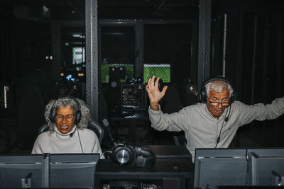 Surprised senior man defeating female friend while playing video game at gaming center