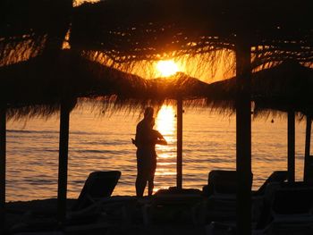 Silhouette man standing by sea against sky during sunset